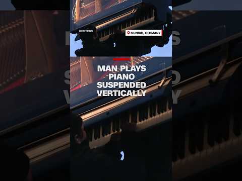 Man plays piano suspended vertically