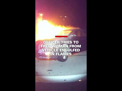 Officer tries to free woman from vehicle engulfed in flames
