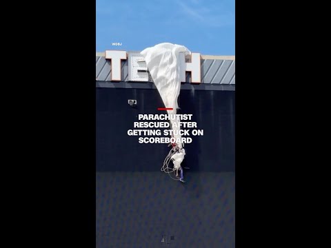 Parachutist rescued after getting stuck on scoreboard