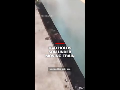 Dad holds son under moving train
